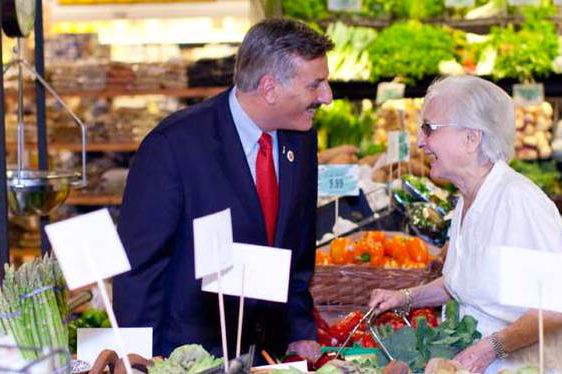 David Weprin distracts an older constituent with his amusing moustache while slowly reaching into her basket to steal a shiny red apple